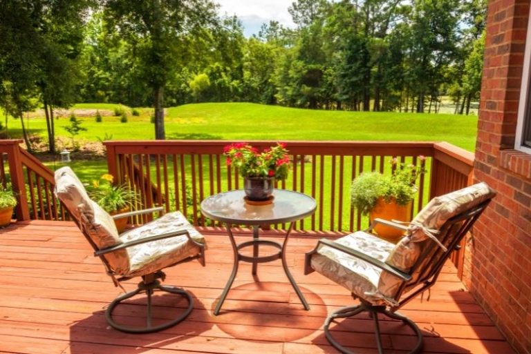 Timber deck with outdoor table and chairs overlooking a backyard lawn